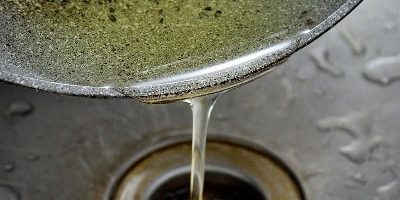 Pouring cooking oil from a pan down a sink drain | S&J Plumbing and Gasfitting