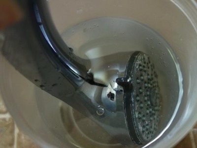 Showerhead being cleaned in a bucket of cleaning solution | S&J Plumbing and Gasfitting